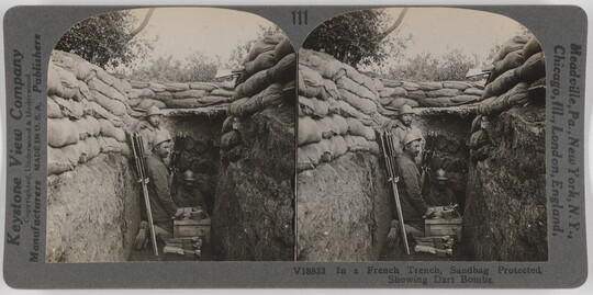 Two almost identical side-by-side black-and-white photographs of three soldiers in a trench topped by a wall of sandbags.