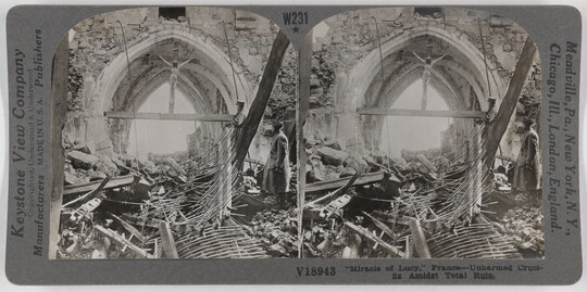 Two almost identical side-by-side black-and-white photographs of a ruined church, wood, and other debris on the ground beneath a large crucifix wedged into an archway.