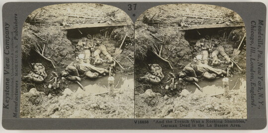 Two almost identical side-by-side black-and-white photographs of human remains in a muddy war trench.