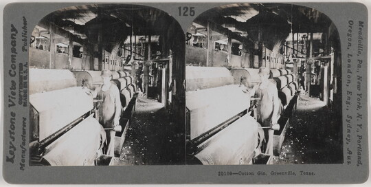 Two almost identical side-by-side black-and-white photographs of a White man standing next to large machinery in a factory.