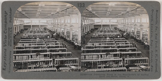 Two almost identical side-by-side black-and-white photographs of the inside of a large factory with rows of frames holding boots and boot molds.