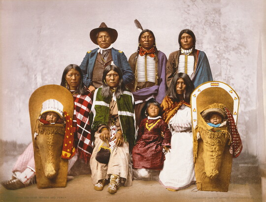 A color photograph of an Indigenous family, including two babies in cradleboards.