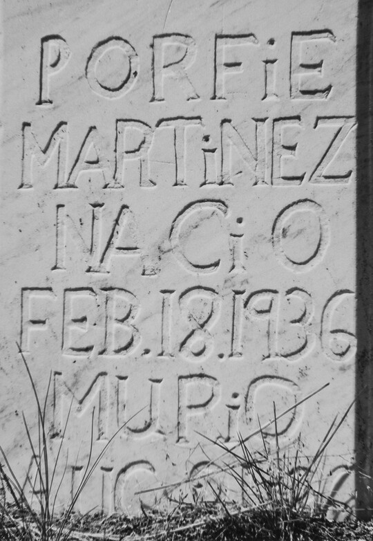 A close-up, black-and-white photograph of inscribed text on a marble gravestone.