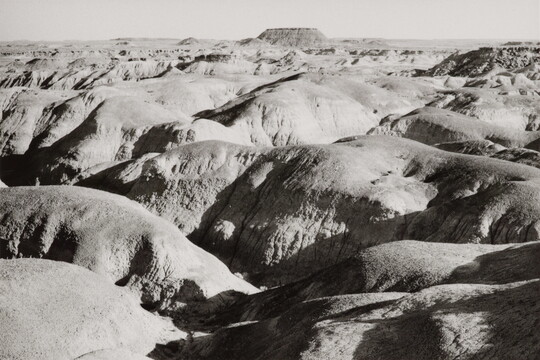 A black-and-white landscape photograph of sunlight on large, round desert rock formations.