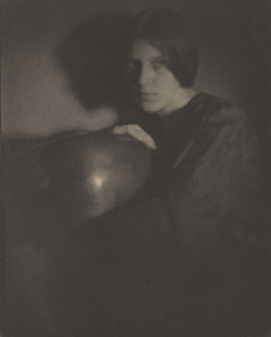 A black-and-white photograph of a White woman in dark clothing holding a bowl.