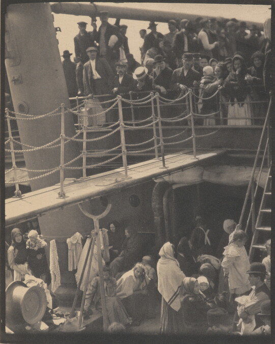 A black-and-white photograph of people outside on two decks of a crowded ship.