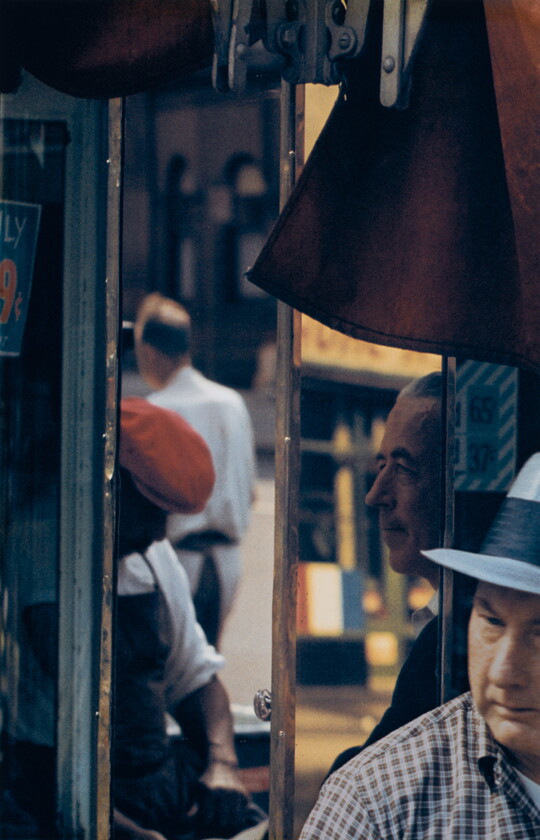 A color photograph of a four men at various angles captured in window reflections.