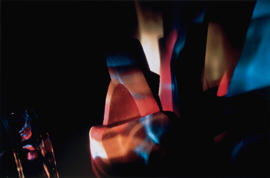 An abstract color photograph of blue, red, and orange light illuminating unknown objects.
