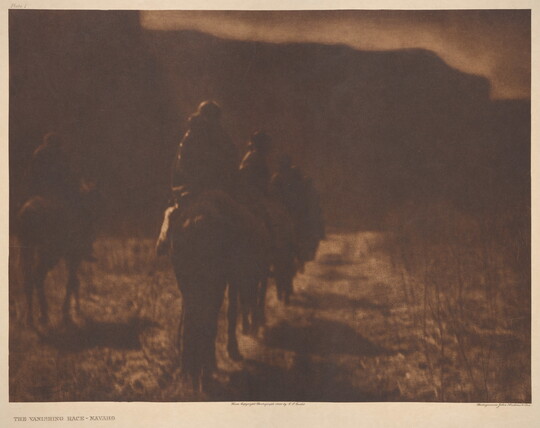 A dark, sepia-toned photograph of people on horseback riding away from the viewer.