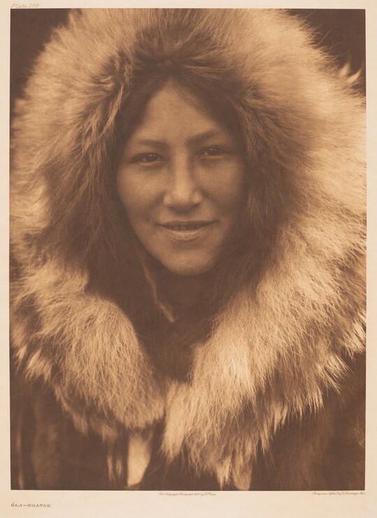 A sepia-toned portrait photograph of an Indigenous person with a fur hood framing their face.