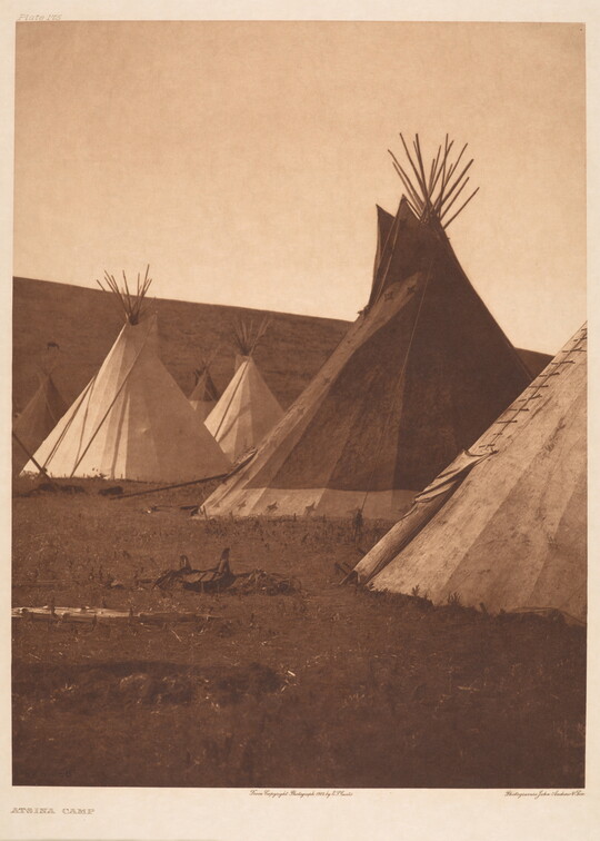 A sepia-toned photograph of a tipi camp.