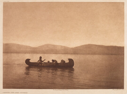 A sepia-toned photograph of people in a canoe on calm water.