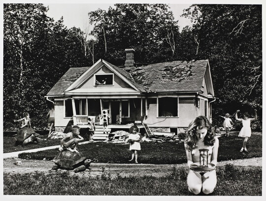 A black-and-white photograph of superimposed children playing on the lawn of an abandoned house.