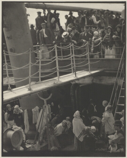 A black-and-white photograph of people outside on two decks of a crowded ship.