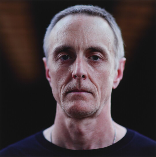 A color photograph of the head and shoulders of a White man with short gray hair and a serious facial expression.