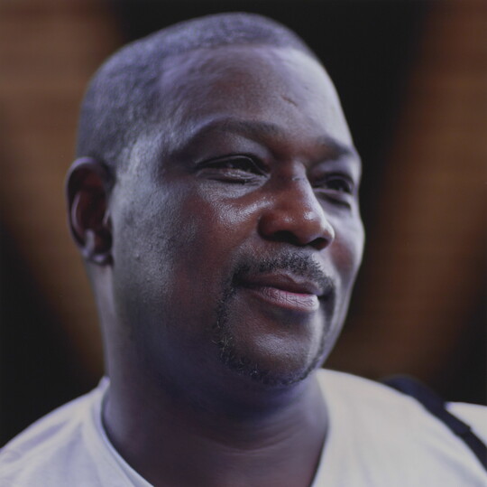 A color photograph of the head and shoulders of a smiling Black man with a goatee and short hair.