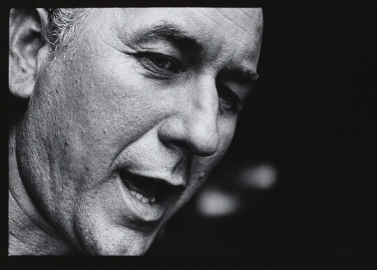 A black-and-white close-up photograph of the face of a White man who appears to be speaking.