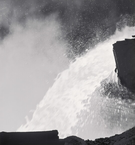 A black-and-white photograph of a close up of molten metal being poured.