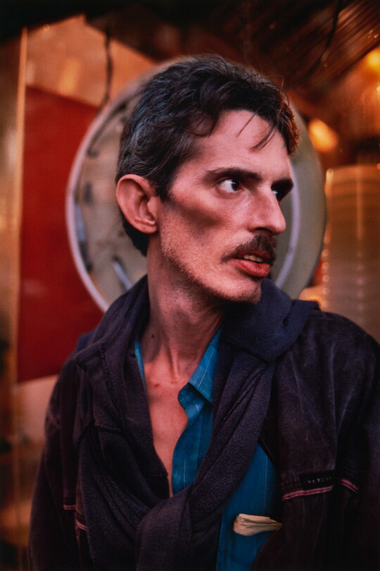 A color portrait photograph of a White man, head turned in profile, with short brown hair, a mustache, and prominent cheekbones.