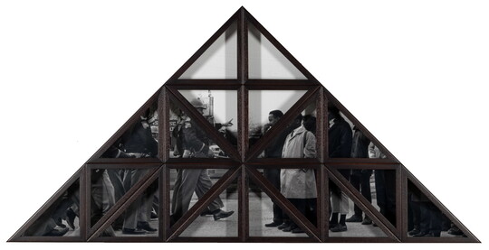 A triangular wood frame divided into smaller triangles over a black-and-white photograph of a group of Black people being confronted by White police officers.
