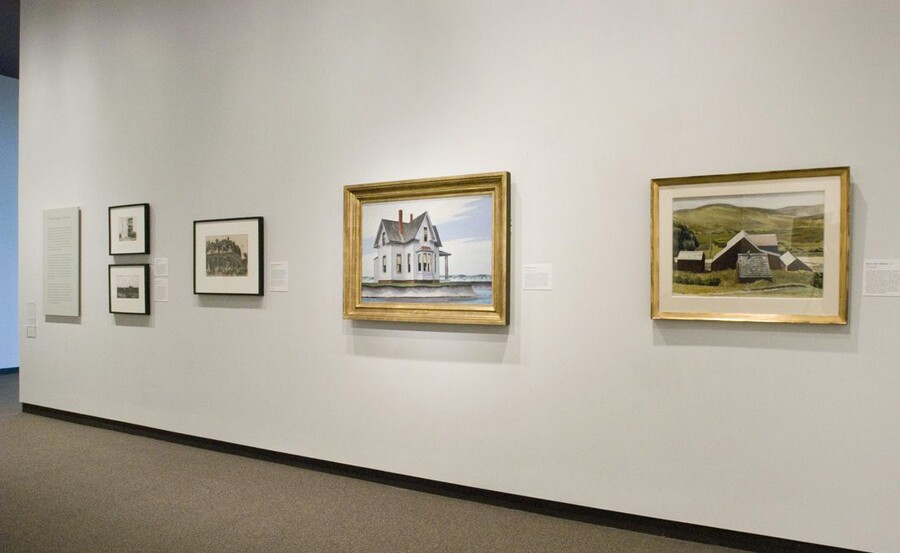 On a cream-colored gallery wall hangs three framed prints and two framed paintings.