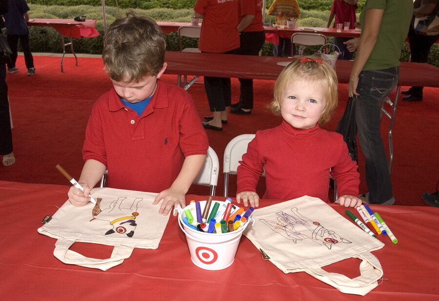 Two children coloring on canvas bags.