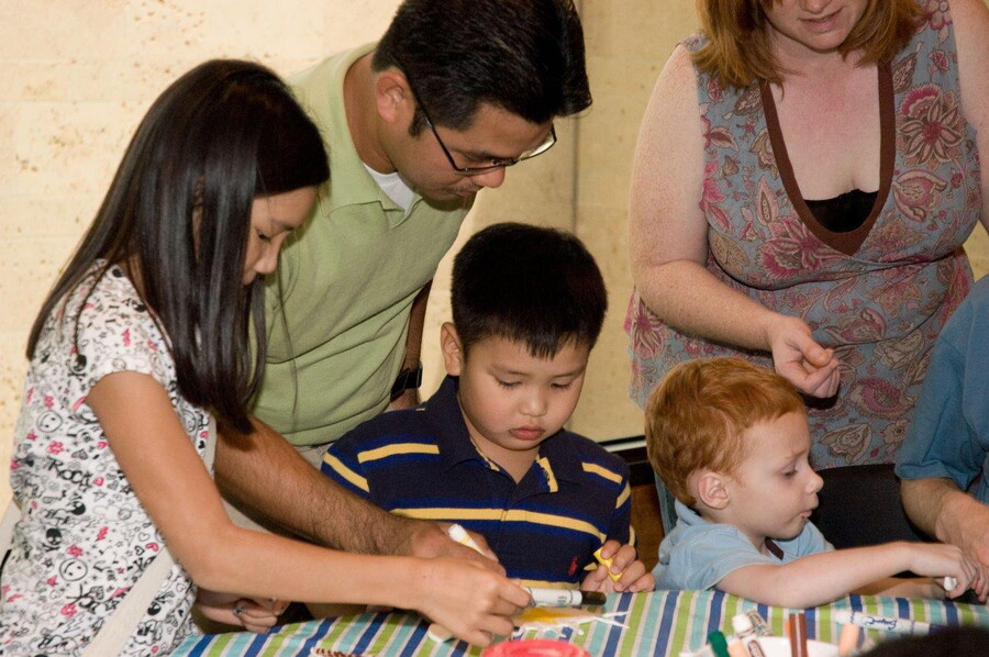 A family gathers around a table to work on an art activity.