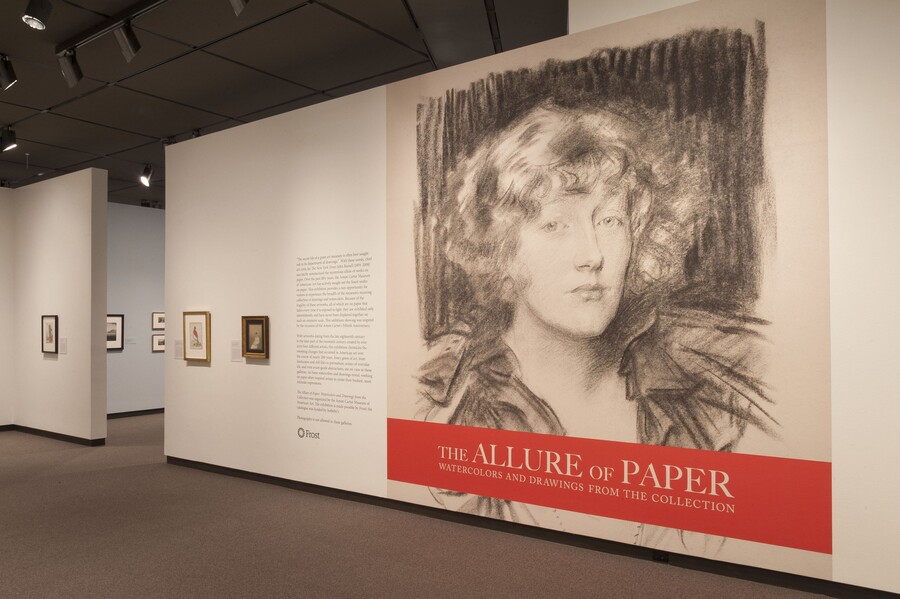 Exhibition title wall showing the title in white on an orange block underneath a large-scale reproduction of a charcoal portrait of a woman.
