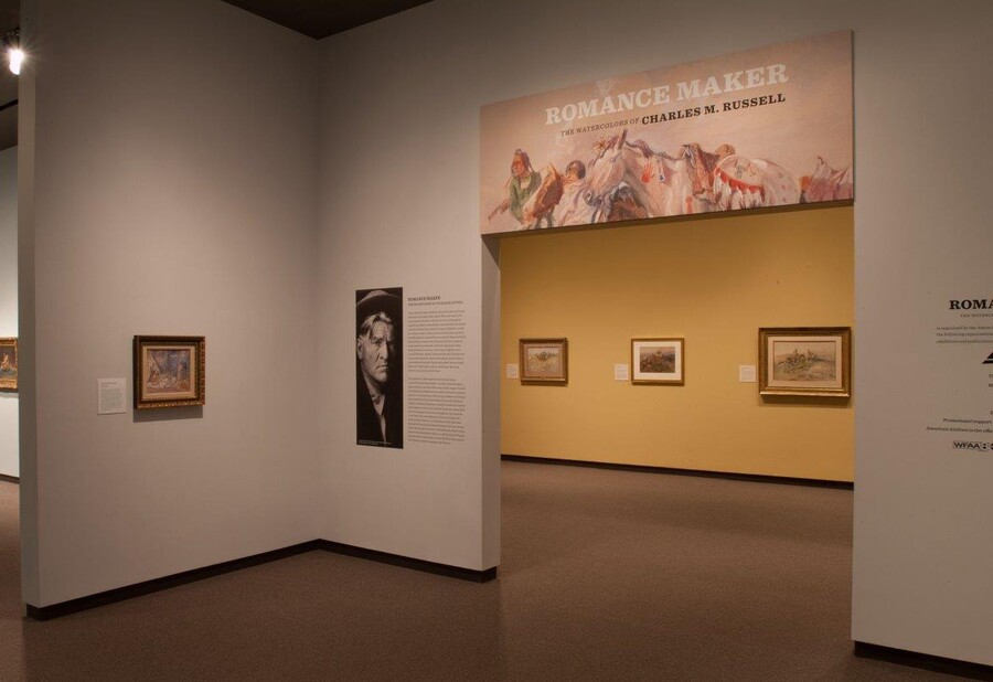 Entrance to exhibition with main graphic over the entranceway; to the left of the entrance is a black-and-white photo of the artist; through the entrance are several framed artworks.