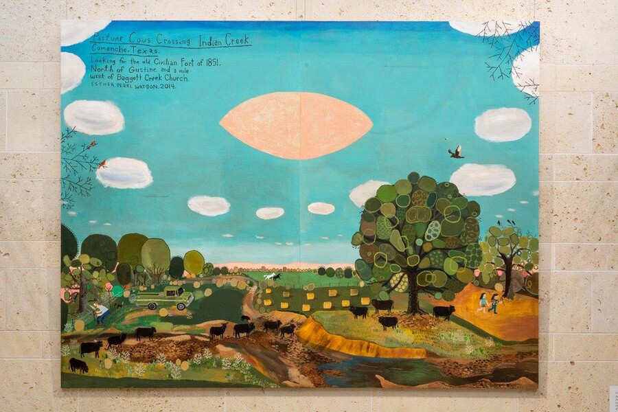 Large-scale painting hanging on a smooth stone wall; the top half shows blue sky, white clouds, and a football-shaped pink UFO; the bottom half shows rolling green hills and pastures, trees, and a herd of black cows.