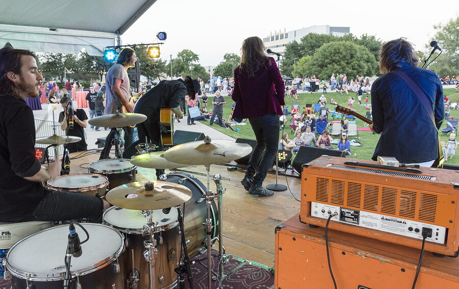 View from behind of a band performing for people gathered on the Carter&#039;s grassy lawn.