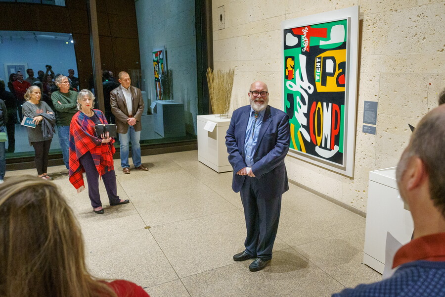 man standing in front of painting interacting with group of people