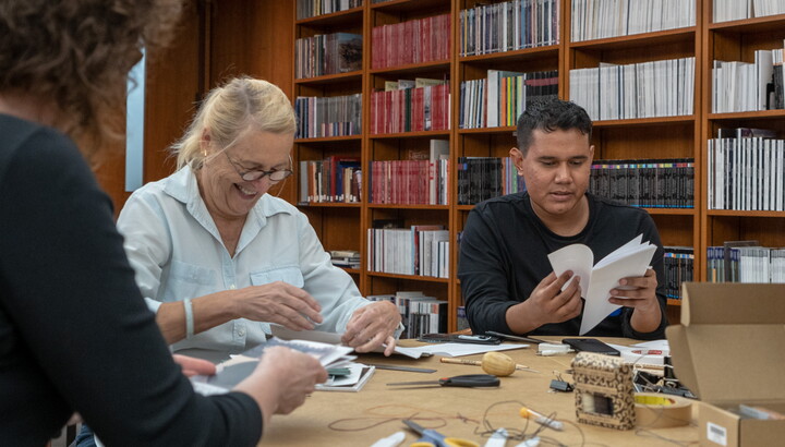 Two adults at a table make books.