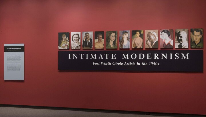 A red title wall with a black panel containing the exhibition title; above it are 11 panels featuring portraits of people.