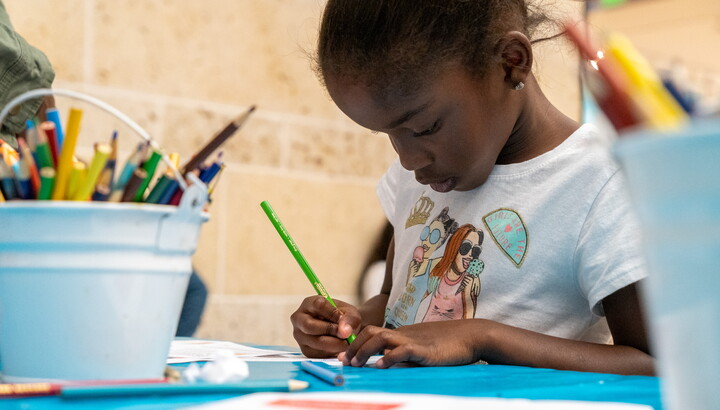 A child is focused on her art project at a table in the Carter's Atrium.