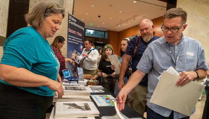 Adult guests at the Carter talk to a museum educator standing at a table full of materials.