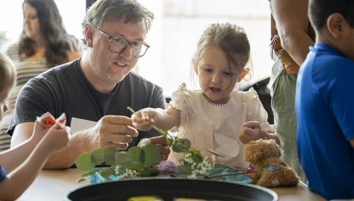 An adult and child make art together at a table in the Carter's Family Pop-Up space.