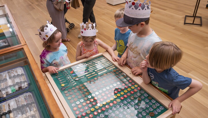Five children stand around an open drawer in "The Texas Cabinet" looking at its contents.