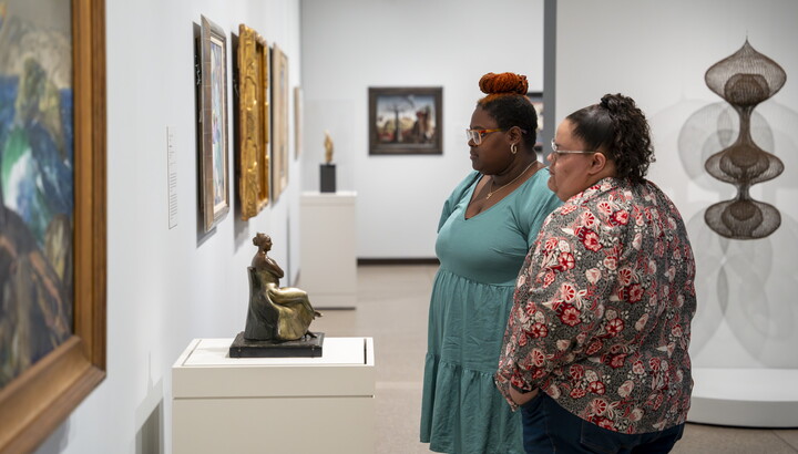 Two women look at artwork on the wall of a Carter gallery.