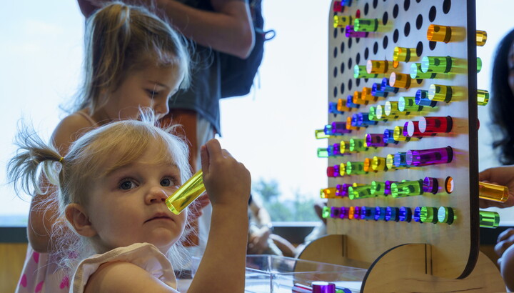 Two children play with large colored pegs and a pegboard in the Carter's Pop-Up Space.