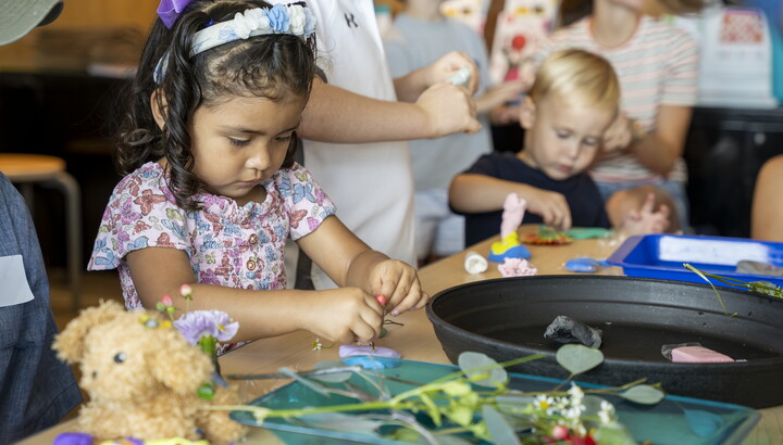 Two toddler-age children make art next to each other at a table in the Carter's Family Pop-Up Space.
