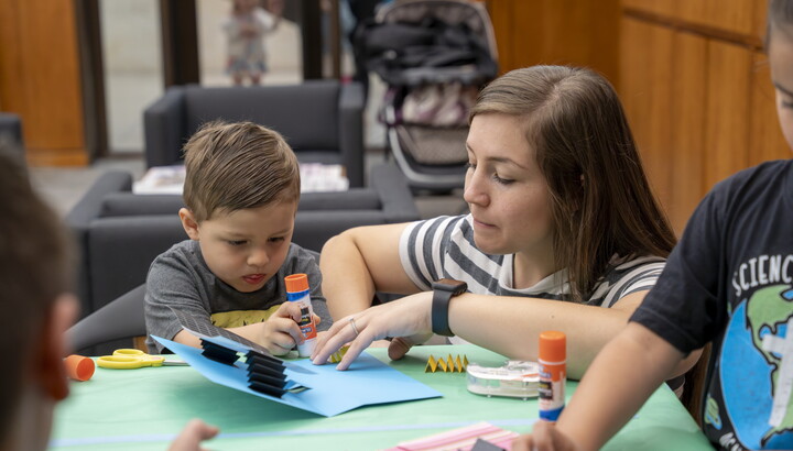 A young White woman and a child make art at a table in the Carter's Library.