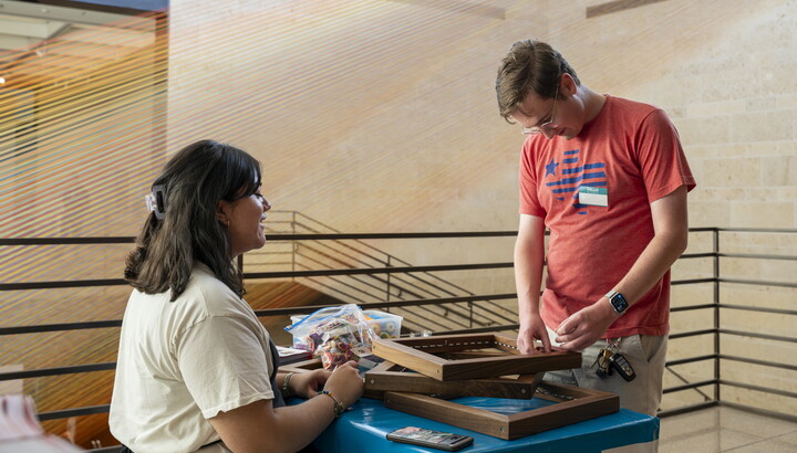 A White man talks to a Carter educator at a table in the Atrium.