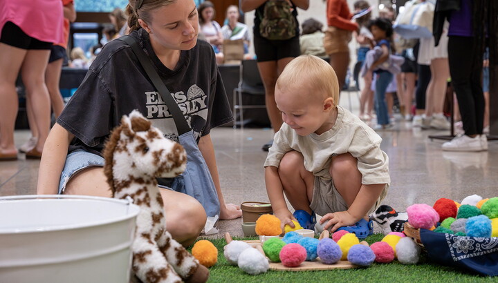 A small child plays with colorful pom-poms in the Carter's Atrium.