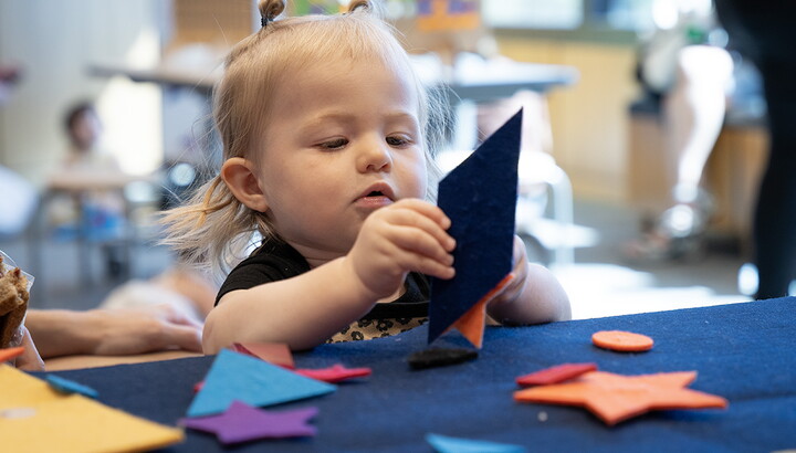 A young child plays with colored paper and felt shapes at a table in the Carter's Atrium.