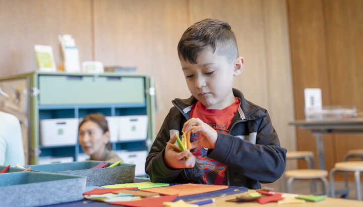A light-skinned child makes art at a table in the Carter's Family Pop-Up Space.