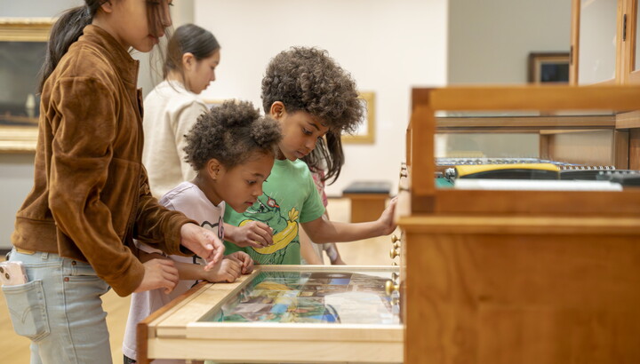 Children of a variety of ages look at the drawers in "The Texas Cabinet" in a Carter gallery.