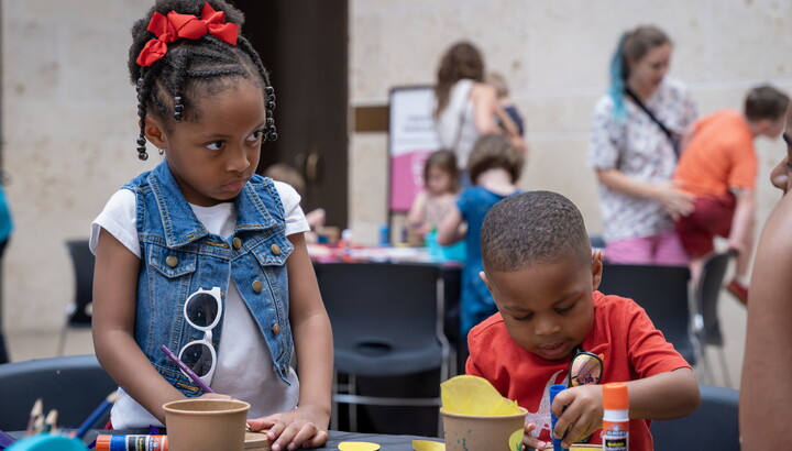 Two Black children use glue sticks and construction paper to make art in the Carter's Atrium.