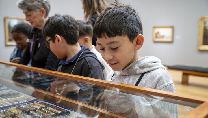 Medium-skinned children look at the objects in "The Texas Cabinet" in a Carter gallery.