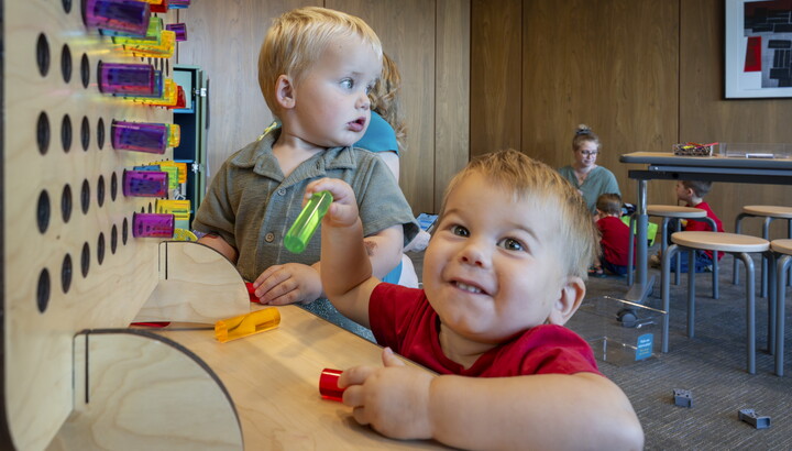 Two very young White babies play with colored pegs in the Carter's Family Pop-up Space.